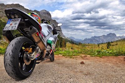 Motorcycle parked on road by field against sky