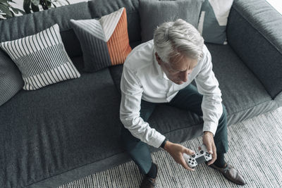 Businessman playing video game while sitting on sofa at office