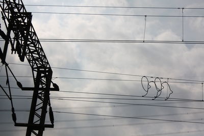 Low angle view of silhouette electricity pylon against sky