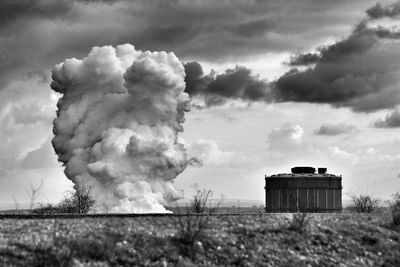 Smoke emitting from field against sky