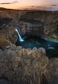 Scenic view of waterfall against sky during sunset