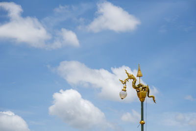 Low angle view of weather vane against blue sky