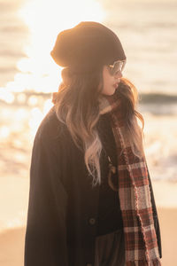 Side view of young woman standing at beach