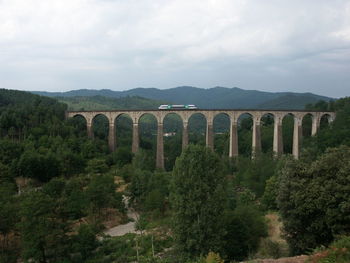 Train on railway bridge over landscape against sky