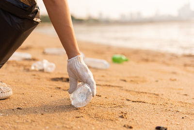 Low section of man standing on sand at beach