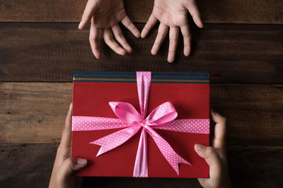 Directly above shot of hands with gift box at table