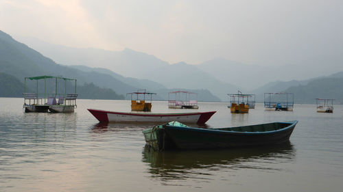 Boats moored in sea against mountains