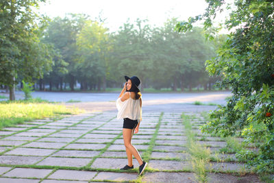 Rear view of woman standing by plants against trees