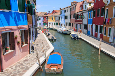 Boats moored on canal by colorful buildings at burano island