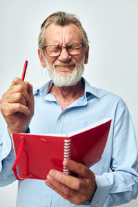 Portrait of senior man using mobile phone against white background