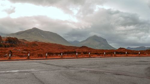 Road by mountains against sky