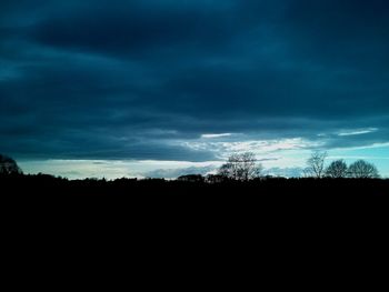 Silhouette of trees against cloudy sky