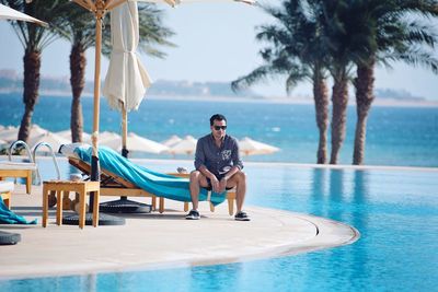 Full length of man relaxing on swimming pool at beach