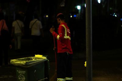 Woman standing on illuminated street at night