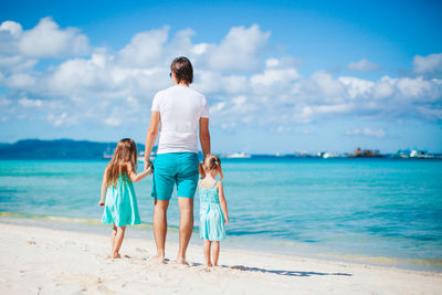 Rear view of women on beach against sky