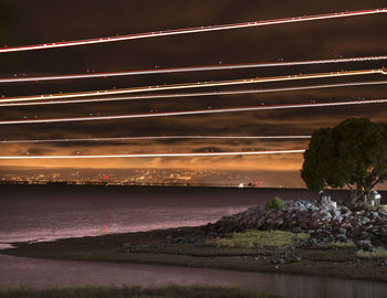 Light paintings over river against sky at night
