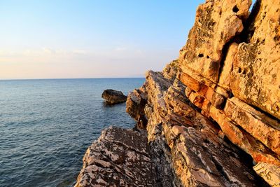 Rock formations by sea against sky