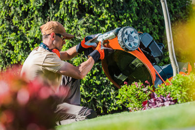 Side view of man repairing lawn mower
