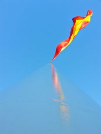 Low angle view of flag waving against clear blue sky