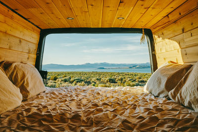 View of mono lake from open doors of camper van with bed in california