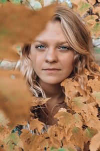 Portrait of young woman amidst autumn leaves