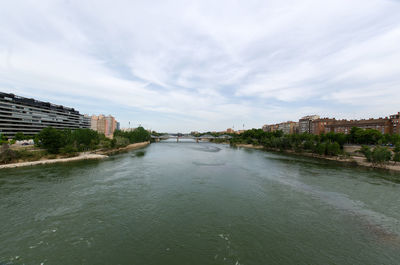 Arch bridge over river against buildings in city