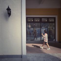 Side view of woman walking against store window
