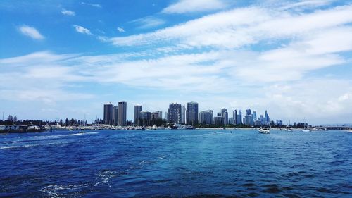 Sea by buildings in city against sky