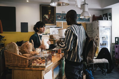 Female entrepreneur talking with customer at checkout counter in food store