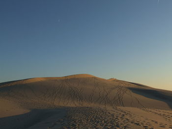 Scenic view of desert against clear blue sky