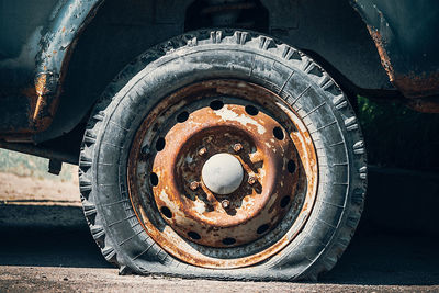 An old flat tire on a rusty car