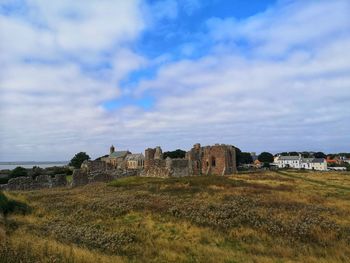 Buildings on field against cloudy sky