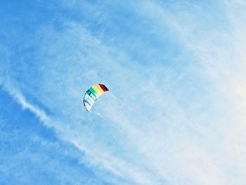 Low angle view of person paragliding against blue sky