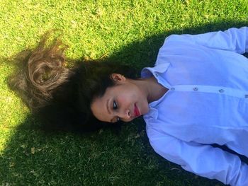 High angle portrait of happy woman lying on grassy field