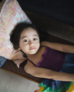 A cute little girl lying on the long chair with rainbow dress in the living-room. top view.