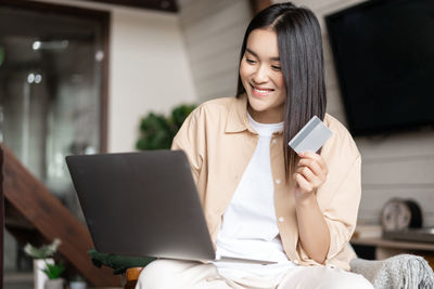 Young woman using phone while sitting at home