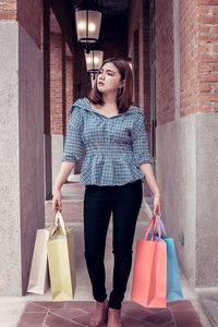 Full length of woman standing against wall