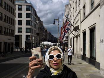 Portrait of man and woman on street against buildings in city