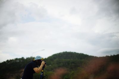 Woman photographing against sky