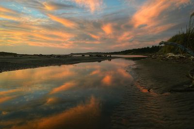 Scenic view of sea against cloudy sky at sunset