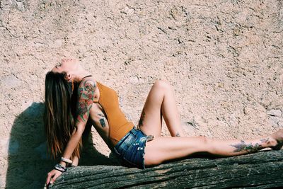 Side view of woman sitting on tree trunk