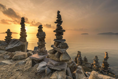 Stack of rocks on shore against sky during sunset