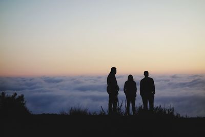 Silhouette men standing against sky during sunset