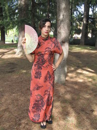Full length of a young woman standing against tree