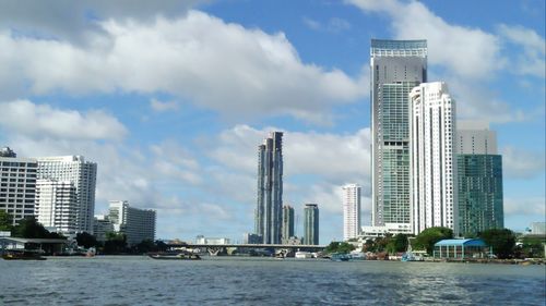 Sea by modern buildings against sky in city