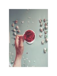 High angle view of hand holding red flower on table