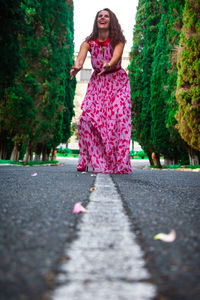 Portrait of woman with pink umbrella on road