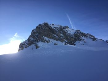 Low angle view of snowcapped mountain against blue sky