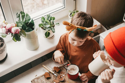 Children drink cocoa with marshmallows and christmas gingerbread man on a wooden background. 