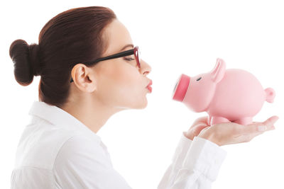 Side view of businesswoman holding piggy bank against white background